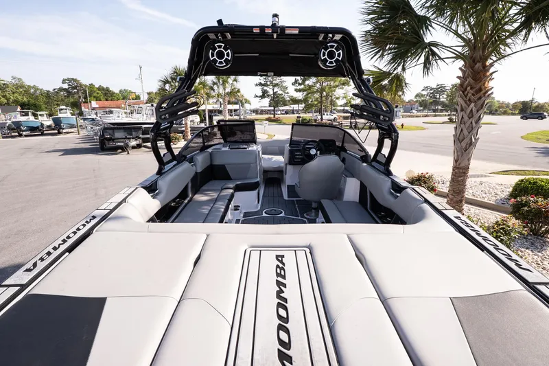 Slide: The Image of 2022 Moomba Max boat interior with sleek seating and modern dashboard, parked outdoors. - 7