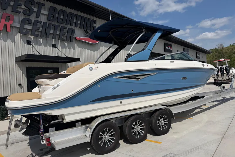 Slide: The Image of 2021 Sea Ray SLX 280 boat on trailer at dealership, blue and white exterior. - 2