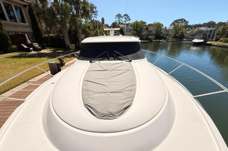 Slide: The Image of 2020 Tiara Yachts C44 Coupe docked by waterfront homes, surrounded by lush greenery. - 40