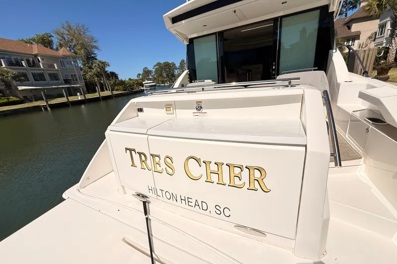 Slide: The Image of 2020 Tiara Yachts C44 Coupe deck with covered seating and table by the water. - 46