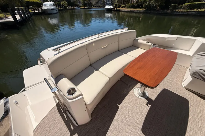 Slide: The Image of 2020 Tiara Yachts C44 Coupe aft deck with wooden table and covered seating. - 53