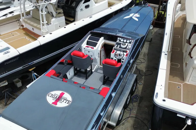 Slide: The Image of 1994 Cigarette 38' Top Gun GT speedboat with red seats, docked among other boats. - 10