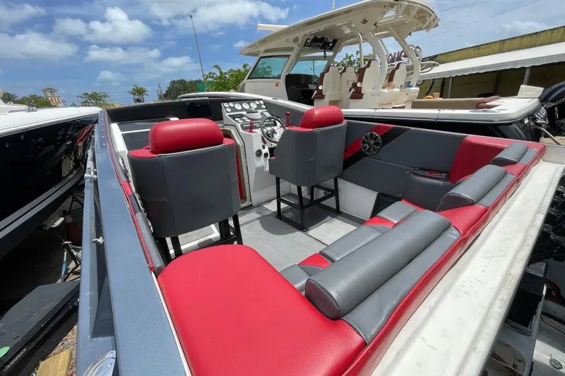 Slide: The Image of 1994 Cigarette 38' Top Gun GT boat interior with red and gray seating under a blue sky. - 16