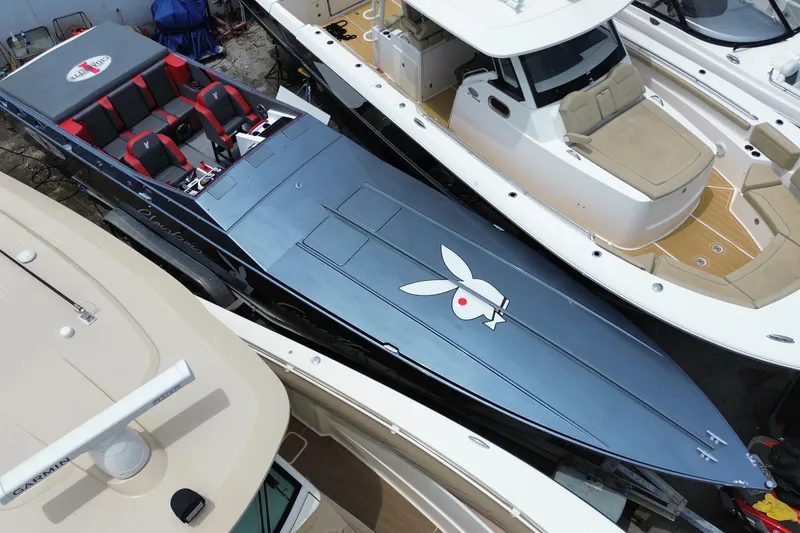 Slide: The Image of 1994 Cigarette 38' Top Gun GT speedboat with custom graphics, docked among other boats. - 9