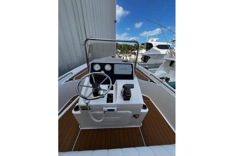 Slide: The Image of 2017 Bulls Bay 2200 boat helm with Garmin navigation, docked near other vessels. - 7