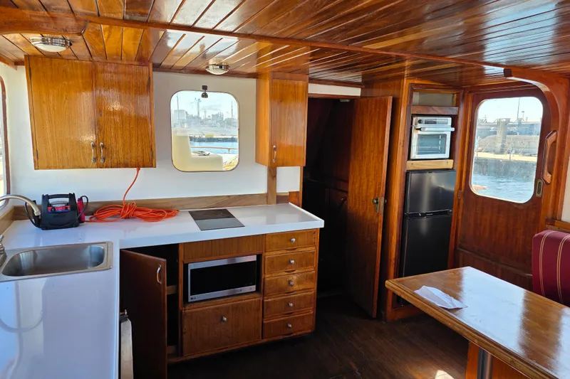 Slide: The Image of 1970 Defver 40 boat interior with wooden cabinetry, kitchenette, and dining area. - 5