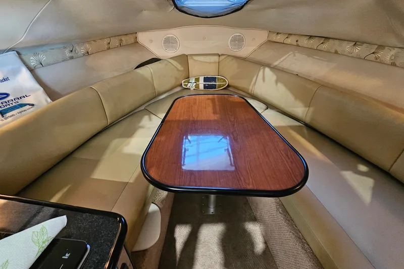 Slide: The Image of 2001 Chaparral Signature 240 cabin interior with beige seating and wooden table. - 13