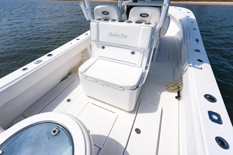 Slide: The Image of 2019 Onslow Bay 33 Tournament boat interior with seating and storage, on calm water. - 23