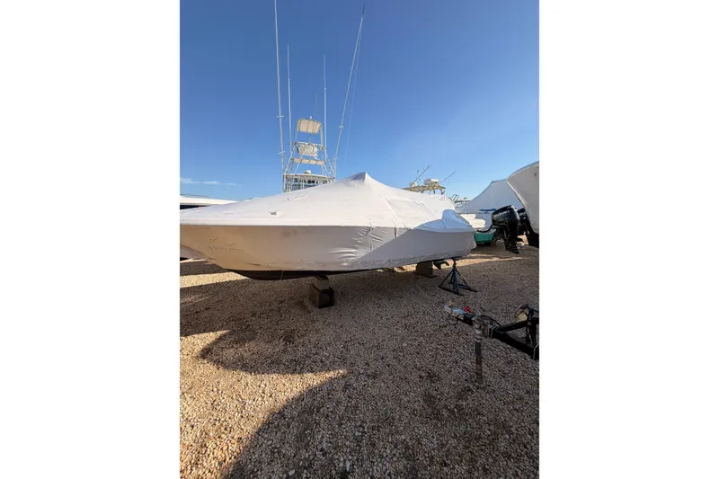 Slide: The Image of 2020 Scout 195 Sportfish boat covered, parked on gravel under clear blue sky. - 3