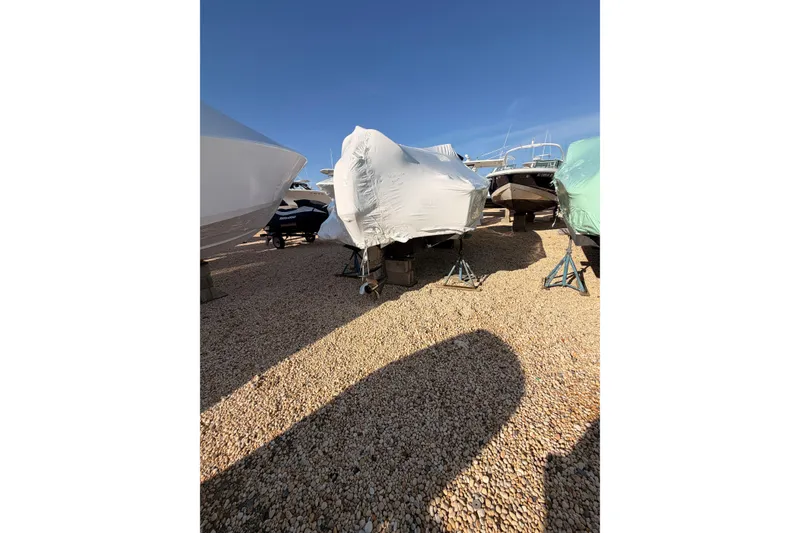 Slide: The Image of Covered 2020 Scout 195 Sportfish boat on gravel lot under clear sky. - 4