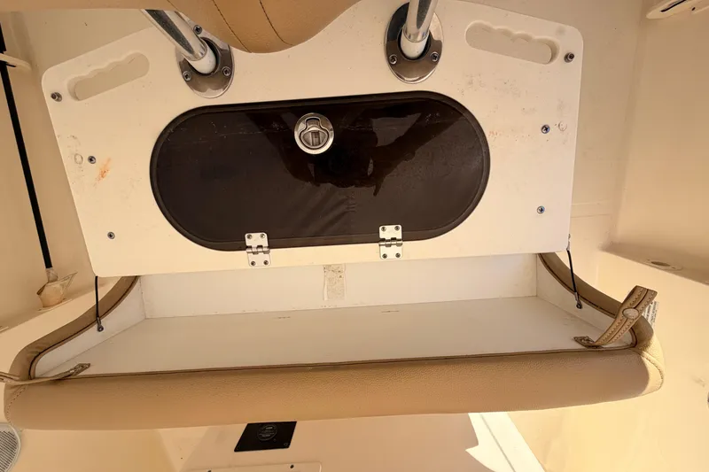 Slide: The Image of 2020 Scout 195 Sportfish boat storage compartment with beige cushion and secure latch. - 7
