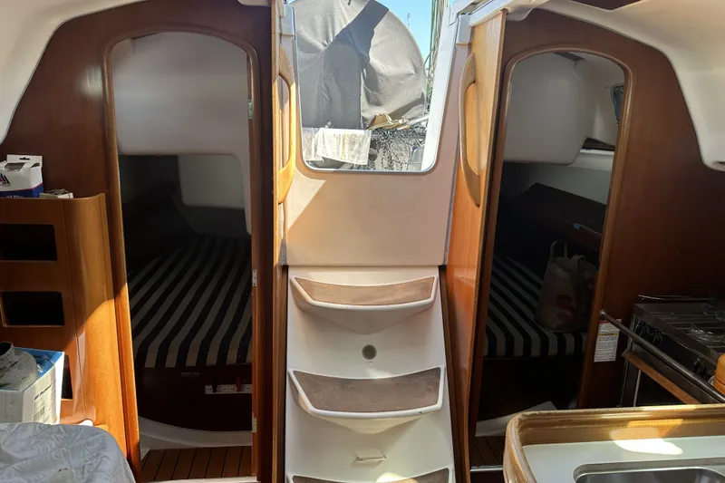 Slide: The Image of Interior of 2002 Beneteau First 36.7 sailboat with striped bedding and wooden finishes. - 10
