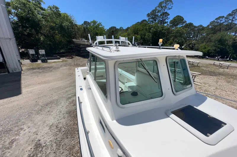 Slide: The Image of 2009 Steiger Craft 255 Miami boat docked outdoors, surrounded by trees and clear sky. - 11