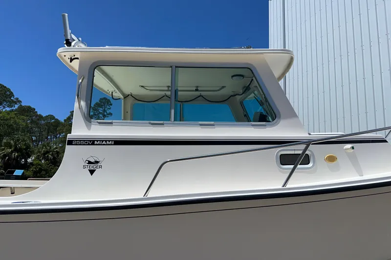 Slide: The Image of 2009 Steiger Craft 255 Miami boat, side view, against blue sky and building backdrop. - 5