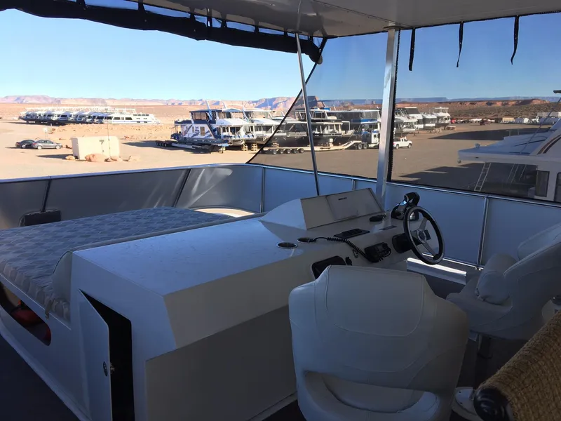 Slide: The Image of Bravada houseboat interior with steering wheel and bed, docked outdoors. - 10