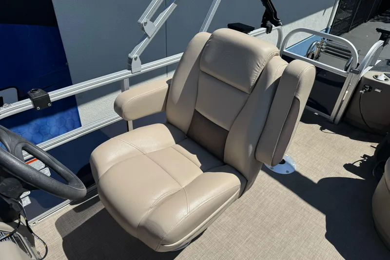 Slide: The Image of 2025 Sun Tracker Bass Buggy 18 DLX captain's chair, beige upholstery, on pontoon boat deck. - 17