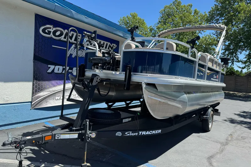 Slide: The Image of 2025 Sun Tracker Bass Buggy 18 DLX pontoon boat on trailer, parked outdoors. - 3