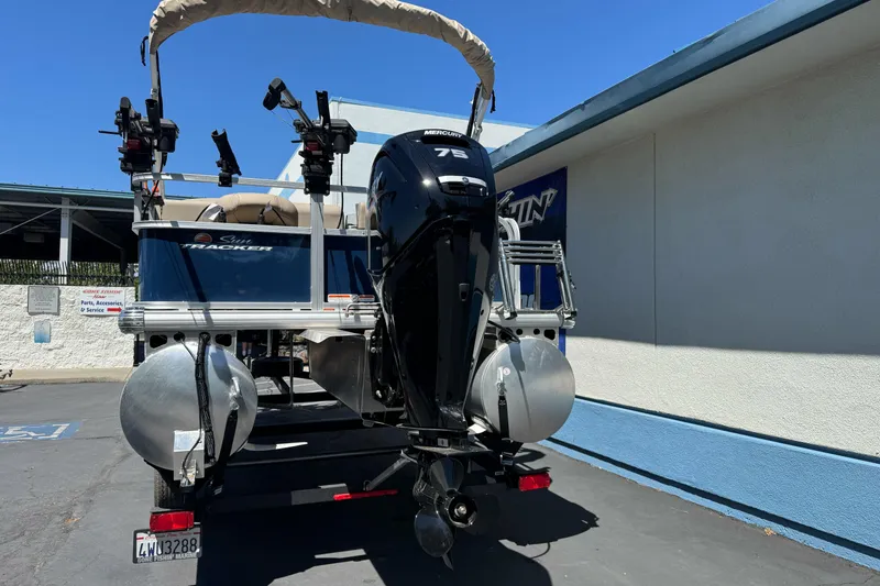Slide: The Image of 2025 Sun Tracker Bass Buggy 18 DLX pontoon boat with Mercury 75 engine, parked outdoors. - 7