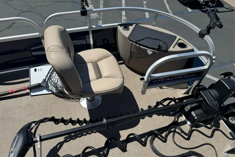Slide: The Image of 2025 Sun Tracker Bass Buggy 18 DLX pontoon boat interior with beige seating and fishing gear. - 9