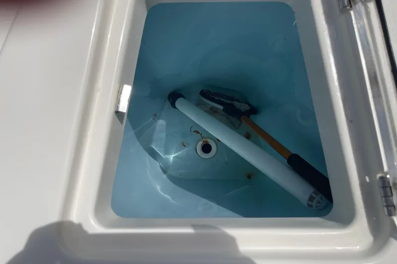 Slide: The Image of Storage compartment on a 2023 Cobia 280 Dual Console boat with cleaning tools inside. - 10