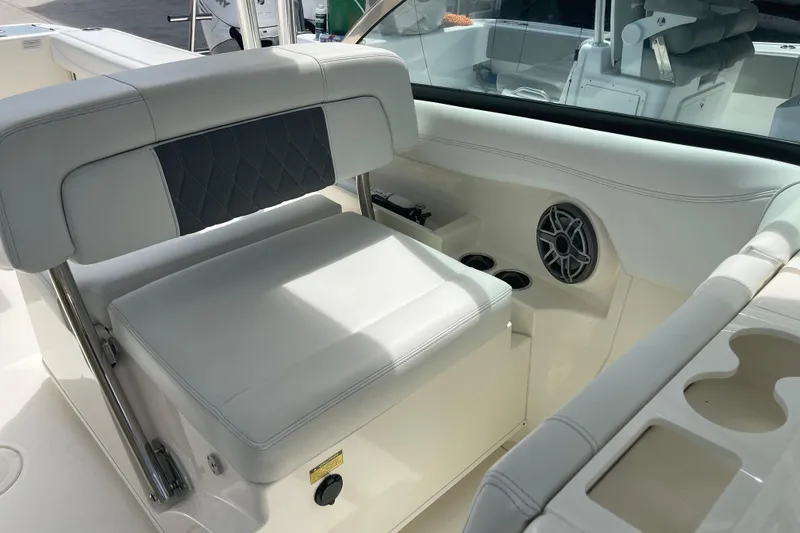 Slide: The Image of 2023 Cobia 280 Dual Console boat interior with cushioned seating and cup holders. - 14