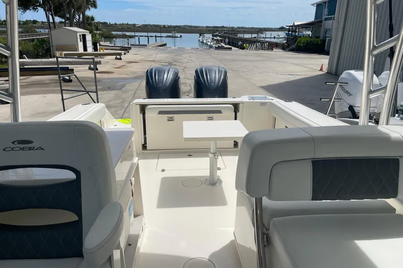 Slide: The Image of 2023 Cobia 280 Dual Console boat interior with seating and table, dockside view. - 17