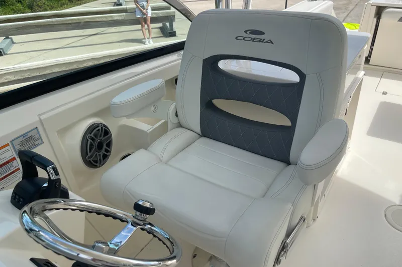 Slide: The Image of 2023 Cobia 280 Dual Console boat interior with steering wheel and cushioned seat. - 18