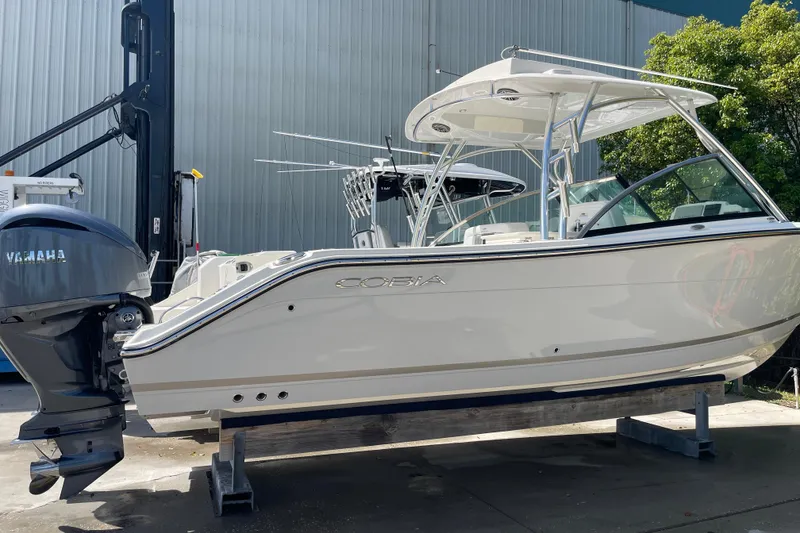 Slide: The Image of 2023 Cobia 280 Dual Console boat with Yamaha engine, displayed outdoors on a stand. - 2