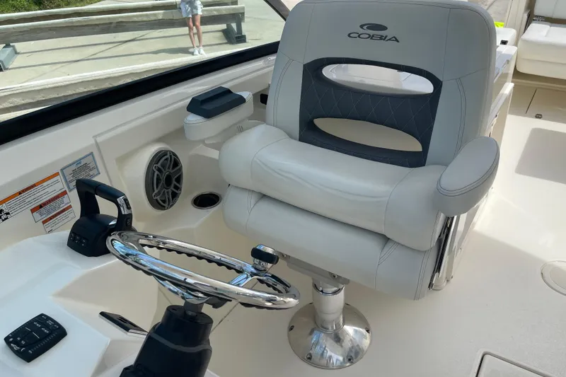 Slide: The Image of 2023 Cobia 280 Dual Console boat interior with steering wheel and captain's chair. - 24