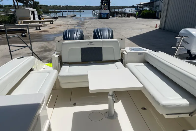 Slide: The Image of 2023 Cobia 280 Dual Console boat interior with seating and table, dockside view. - 32