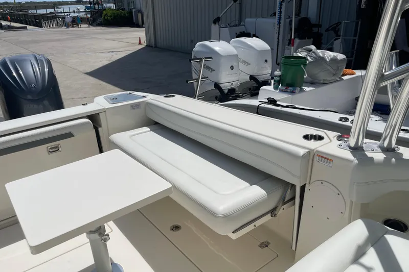 Slide: The Image of 2023 Cobia 280 Dual Console boat interior with seating and table, docked near water. - 33