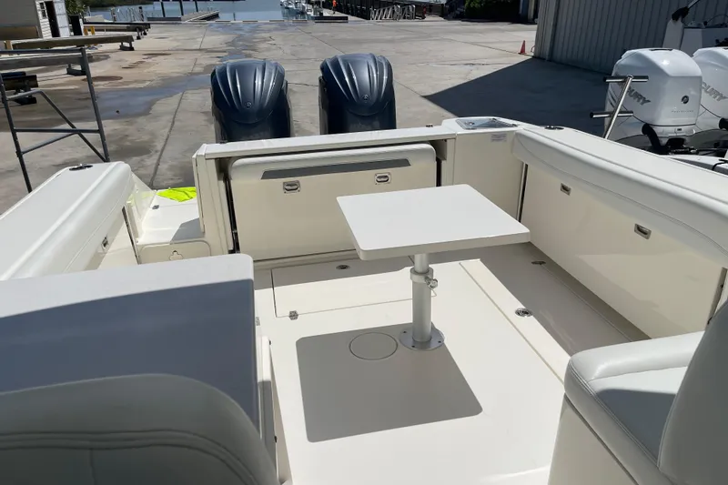 Slide: The Image of 2023 Cobia 280 Dual Console boat interior with seating and table, dockside view. - 34