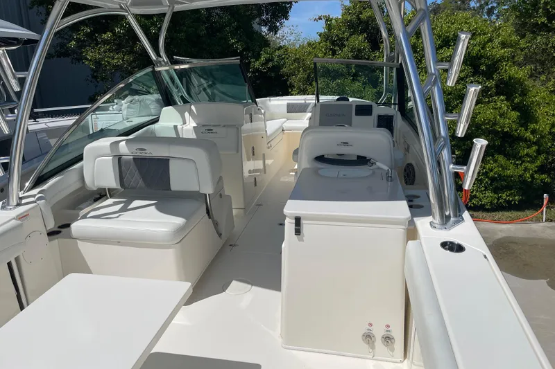 Slide: The Image of 2023 Cobia 280 Dual Console boat interior with seating and helm, surrounded by greenery. - 41