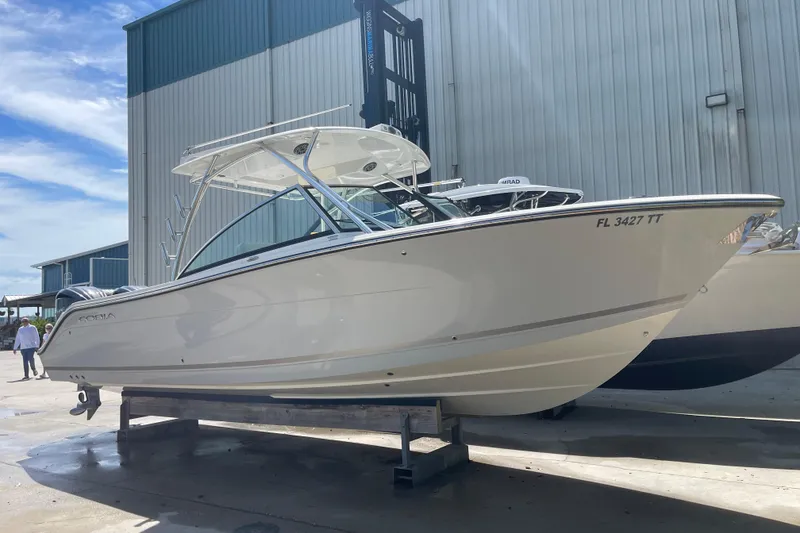 Slide: The Image of 2023 Cobia 280 Dual Console boat displayed outdoors near a large building. - 44