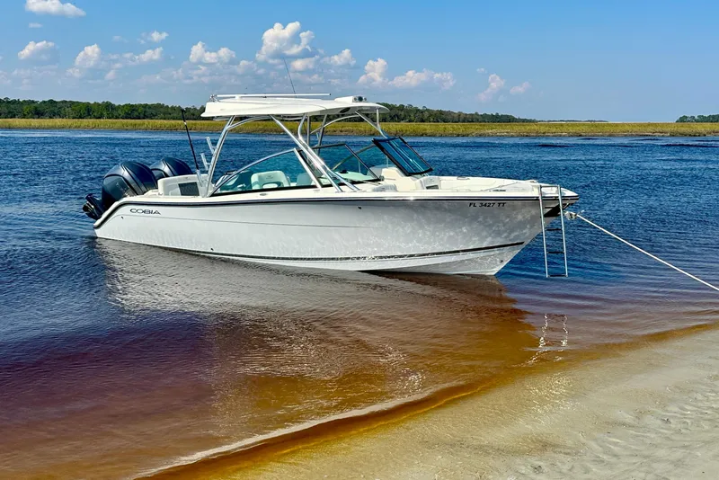 Slide: The Image of 2023 Cobia 280 Dual Console boat anchored on a serene lake with clear skies. - 54