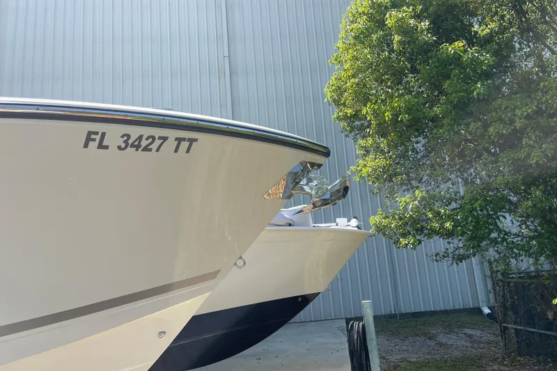 Slide: The Image of 2023 Cobia 280 Dual Console boat docked near a tree and building. - 6