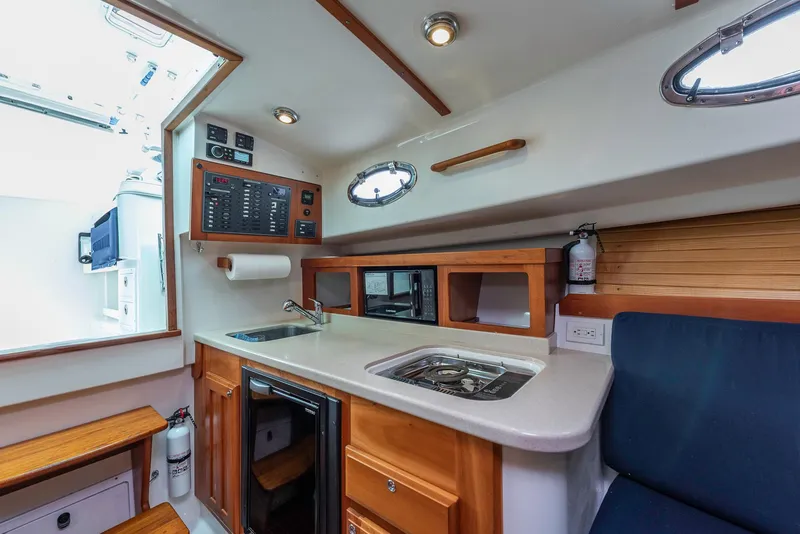 Slide: The Image of 2005 Back Cove Downeast Hardtop interior with kitchenette, sink, and wooden cabinetry. - 10
