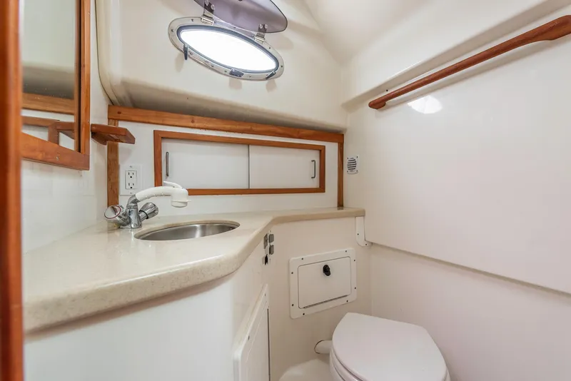 Slide: The Image of 2005 Back Cove Downeast Hardtop boat bathroom with sink, toilet, and porthole window. - 15