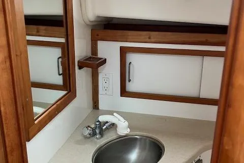 Slide: The Image of 2005 Back Cove Downeast Hardtop bathroom with sink, mirror, and wooden cabinetry. - 16