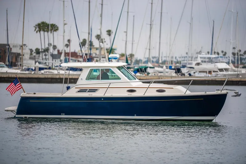Slide: The Image of 2005 Back Cove Downeast Hardtop boat in marina, with American flag, calm water, and sailboats in background. - 3