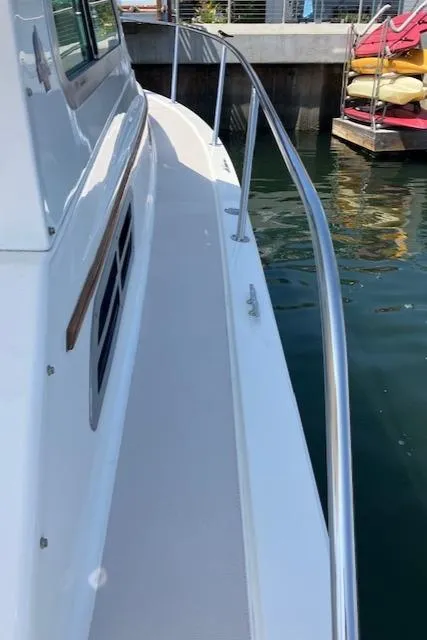 Slide: The Image of 2005 Back Cove Downeast Hardtop boat docked, showcasing sleek side railings and clean white deck. - 30