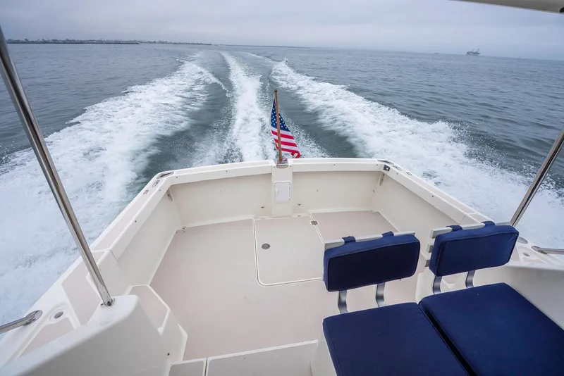 Slide: The Image of 2005 Back Cove Downeast Hardtop boat cruising, American flag, ocean view, wake trail. - 33