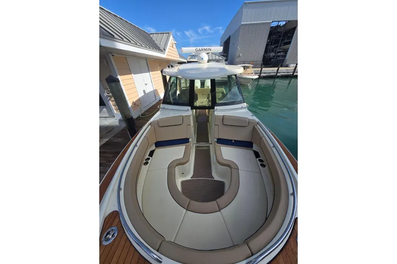 Slide: The Image of 2023 Chris-Craft Calypso 35 boat with elegant seating, docked near modern buildings. - 12