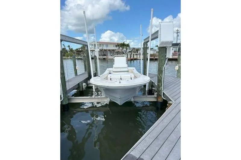 Slide: The Image of 2023 Abaco Skiff 20 boat docked on a lift, with waterfront view and blue sky. - 4