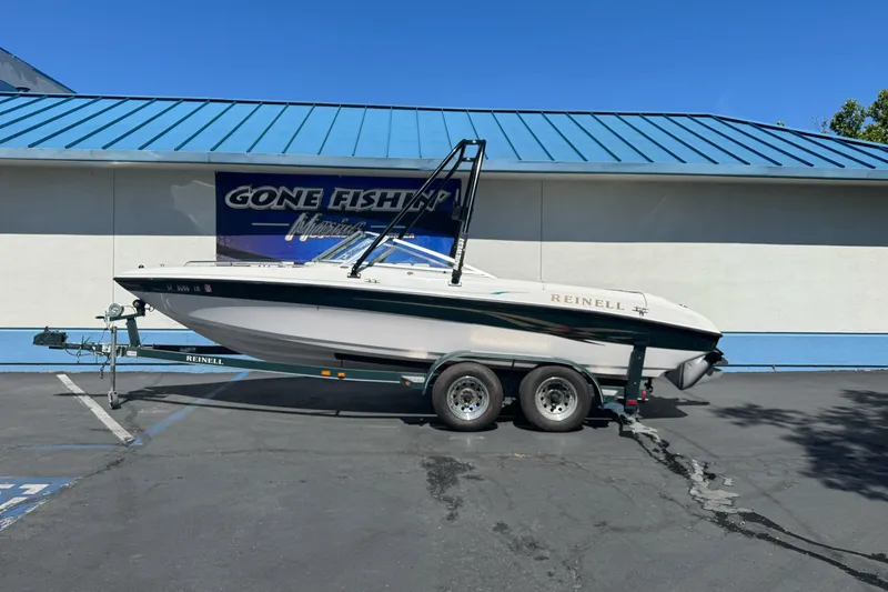 The Image of 2001 Reinell 203 boat on trailer, parked outside a building with blue roof. - 0