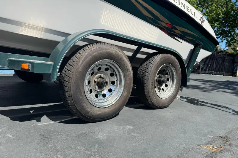 Slide: The Image of Trailer wheels of a 2001 Reinell 203 boat parked on pavement. - 2
