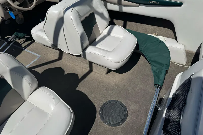 Slide: The Image of Interior of a 2001 Reinell 203 boat with white seating and green cover. - 23