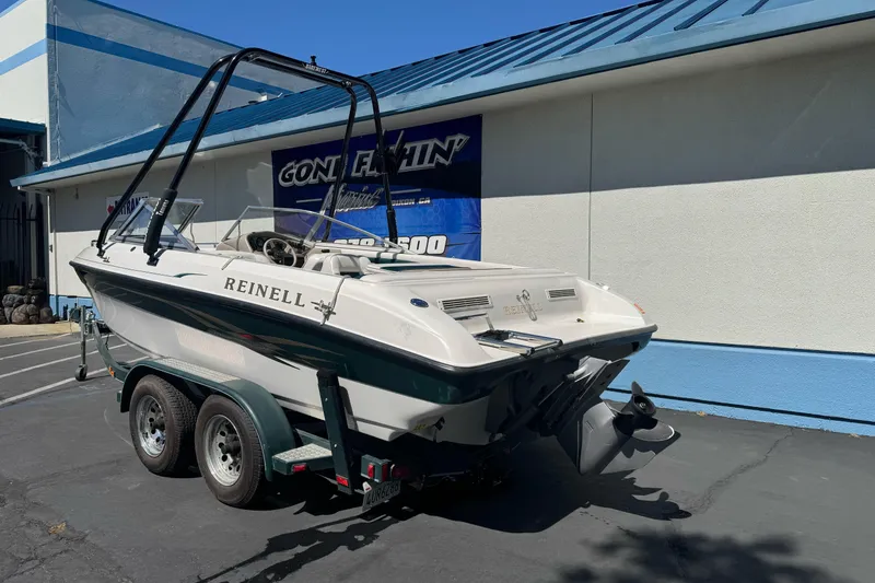 Slide: The Image of 2001 Reinell 203 boat on trailer, parked outside a blue-roofed building. - 6