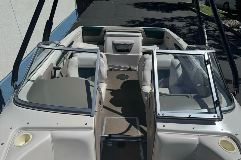Slide: The Image of 2001 Reinell 203 boat interior with seating and windshield, parked on pavement. - 9