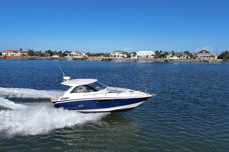 Slide: The Image of 2016 Regal 35 Sport Coupe cruising on a sunny day near waterfront homes. - 2
